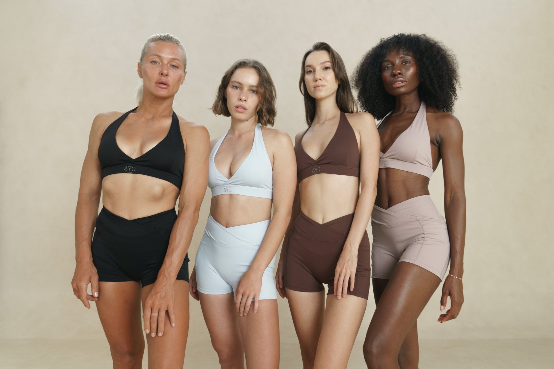 Four women in AYO bra-and-shorts sets in black, ice blue, chocolate and mauve