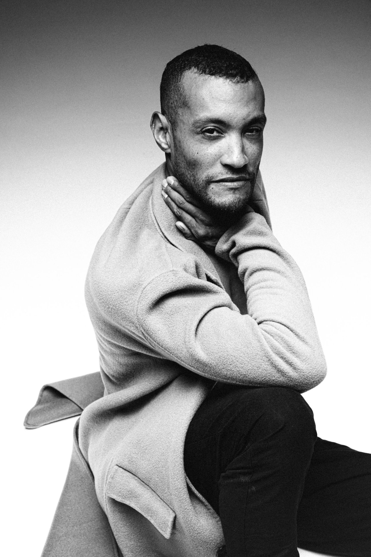 David in a wool coat with his hand on his neck, smiling at the camera