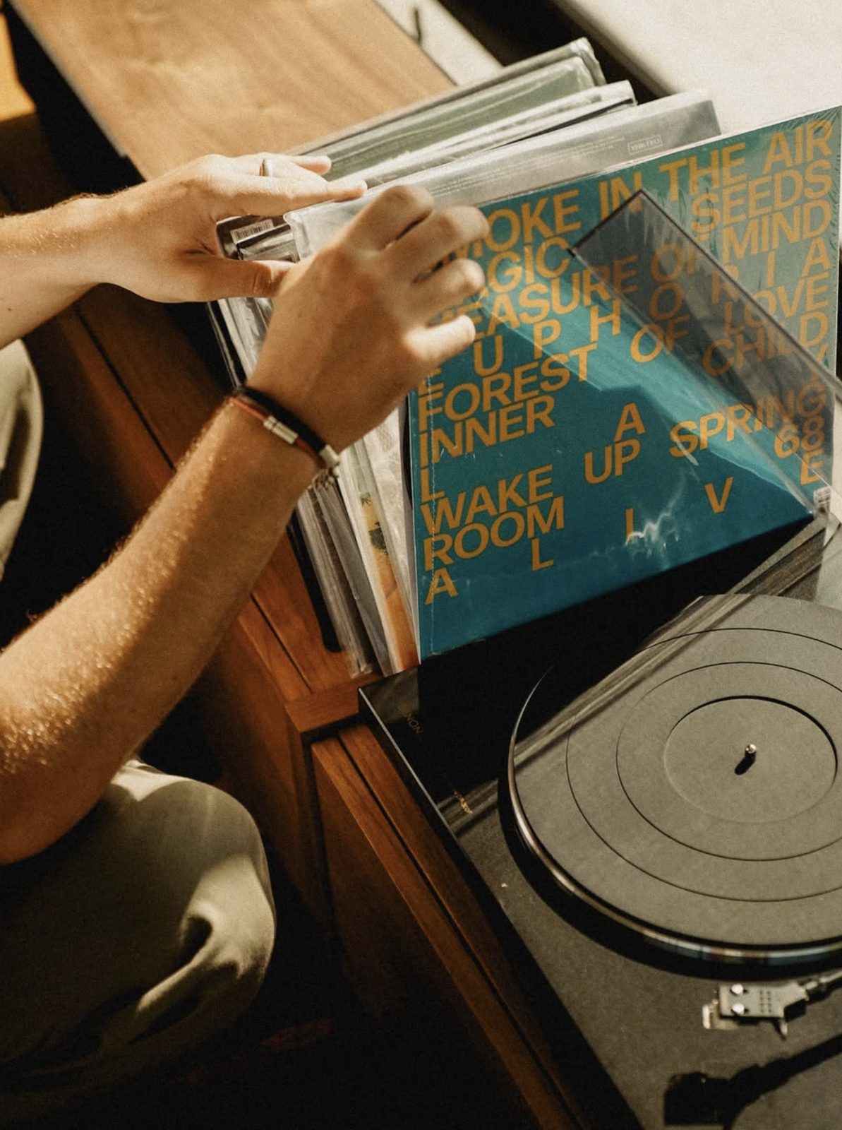 Hands flipping through vinyl records next to a turntable