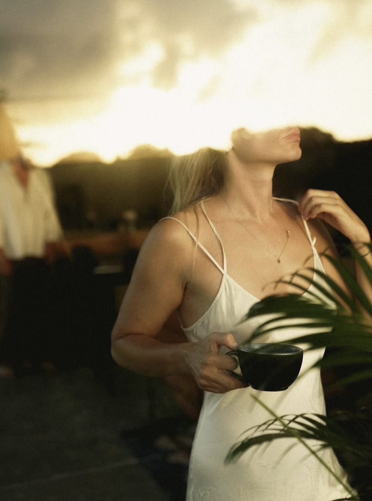 Woman holding a coffee cup at sunrise on the terrace