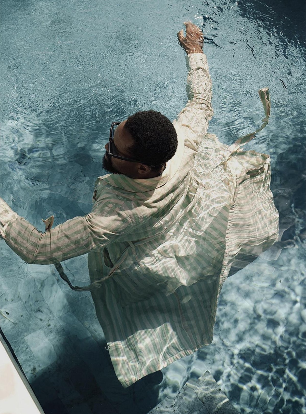Michael in a striped robe floating in a villa pool, seen from above