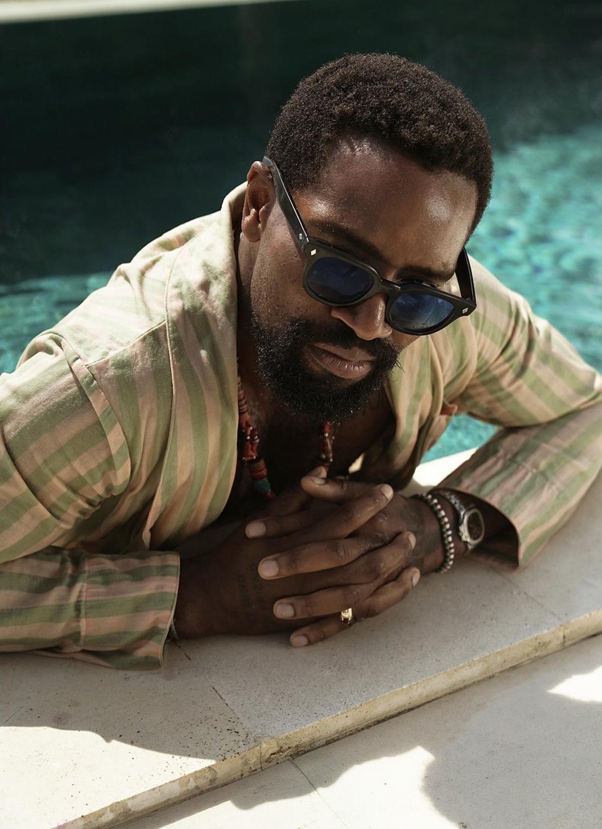 Michael leaning on the edge of the pool in a striped robe