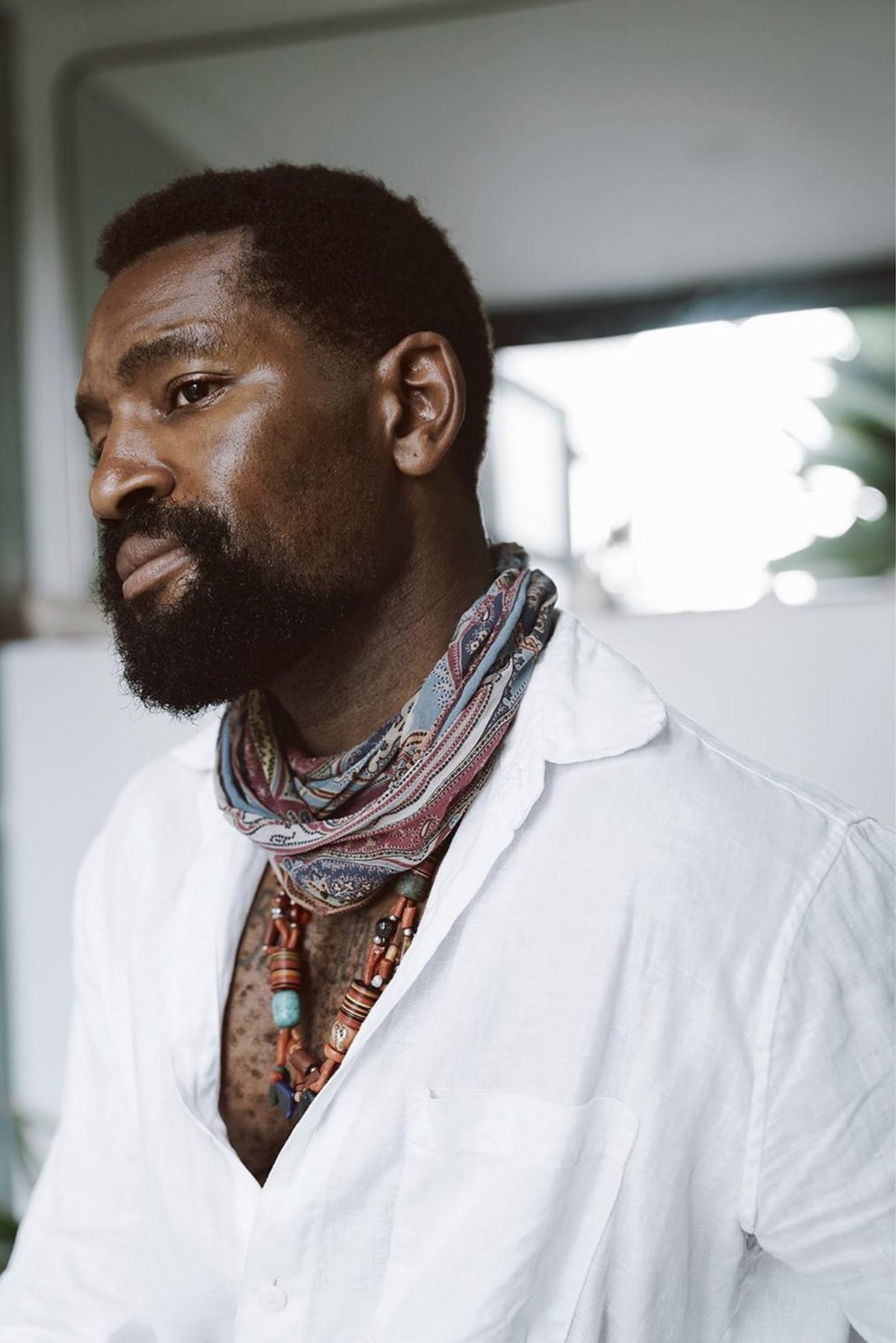 Portrait of Michael in a white shirt and a paisley scarf, looking away