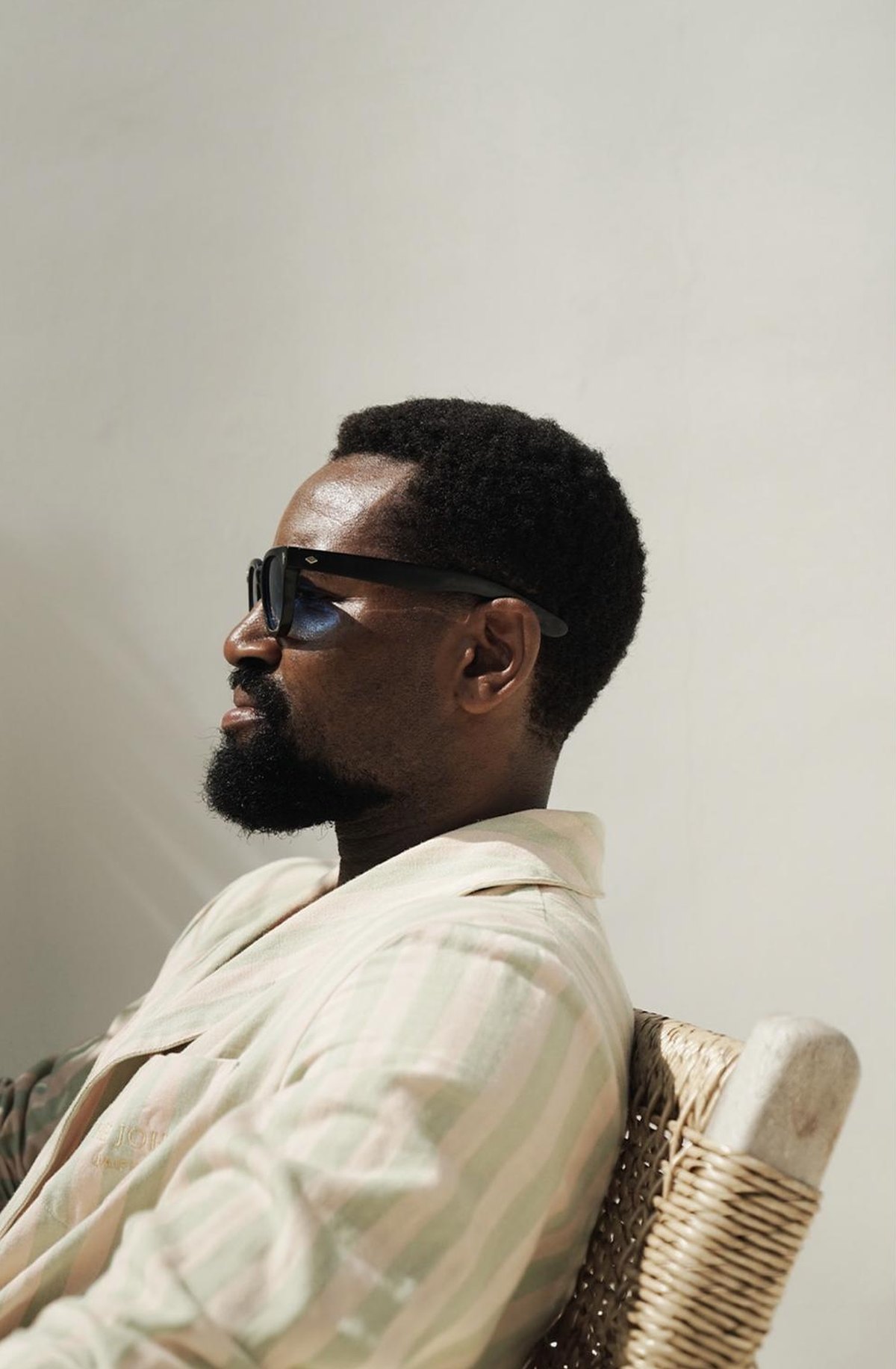 Profile of Michael in sunglasses and a striped robe against a pale wall